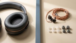 Over-Ear-Kopfhoerer und In-Ear-Monitore mit verschiedenen Ohrstoepsel-Groessen nebeneinander auf warmem Beige